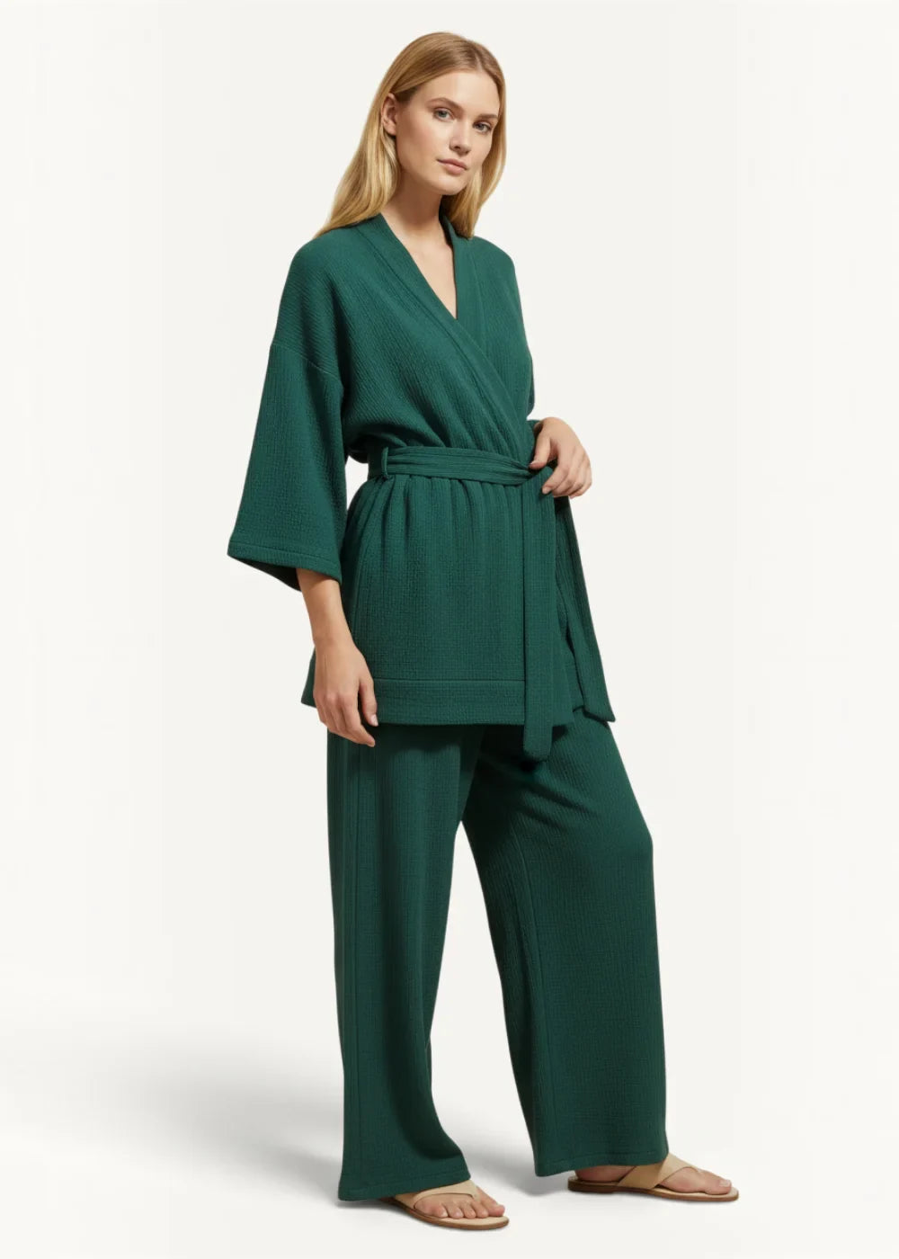 A woman wearing deep emerald green ribbed knit teal kimono pajamas with wide sleeves and high-waisted waist tie trousers