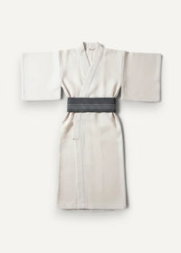 Traditional kimono cream-colored with soft draping wide sleeves and dark gray striped obi belt visible from front