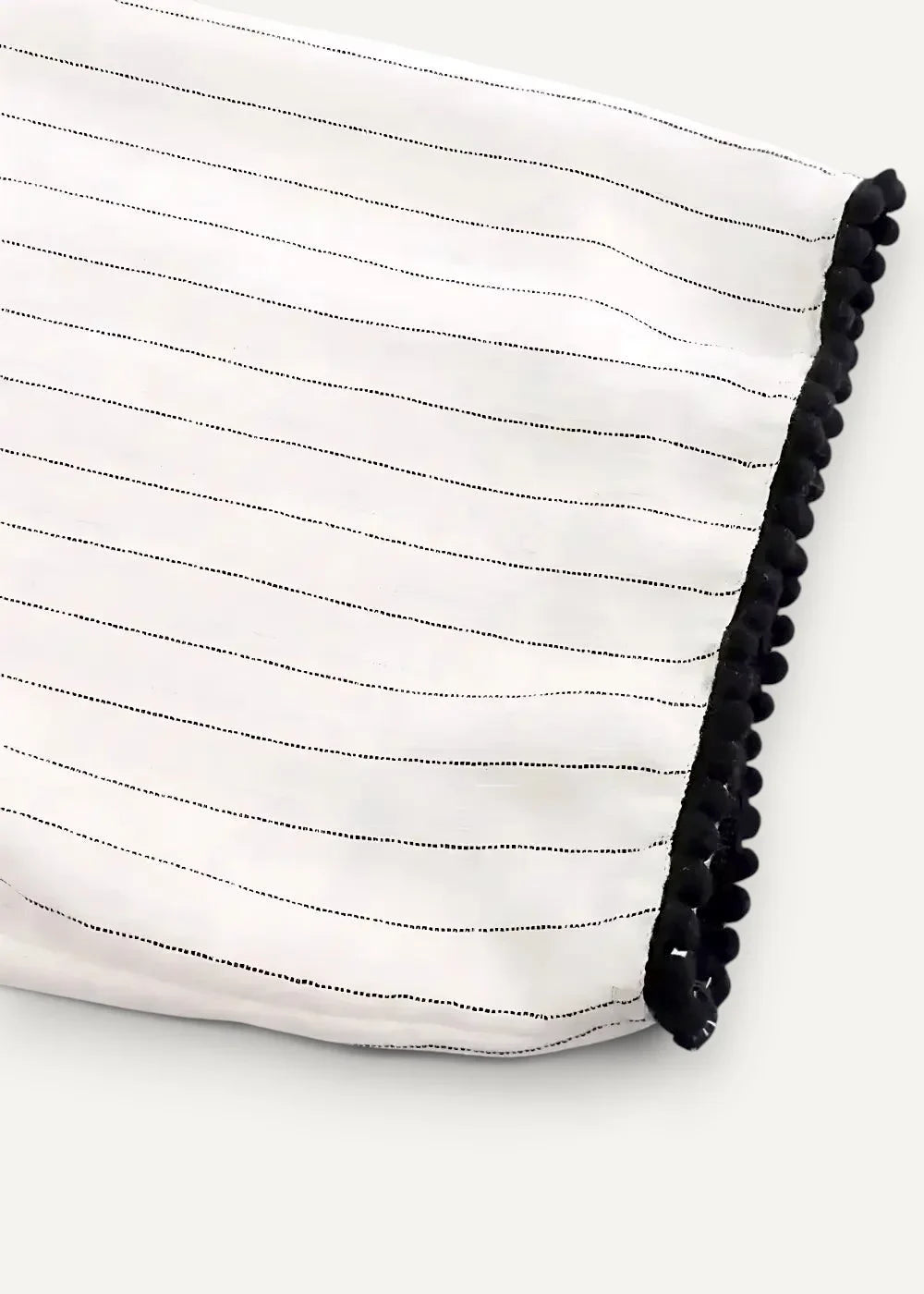 Close-up of the white kimono dress fabric with thin black stripes and a black pom pom border
