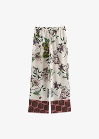Cream-colored wide-leg pants with intricate green leaves and purple floral print and dusty rose hemband with brown motifs