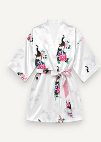 White satin robe with floral and peacock print featuring pink blossoms and black and white birds on glossy fabric