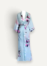 Women’s long silk robe in light blue satin with peacock and pink floral pattern, three-quarter sleeves, and matching belt